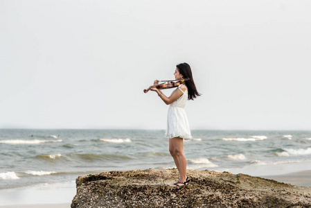 在沙滩上玩小提琴的快乐女人