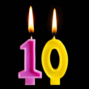 重要日期燃烧生日蜡烛的形式10十图为蛋糕隔离在黑色背景.
