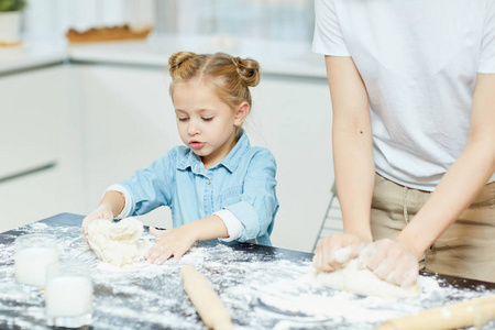 可爱的小女孩, 帮助她的母亲揉面团自制甜甜圈或包子早餐