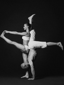 黑白肖像美丽的运动情侣 妇女和男子在白色的衣服做瑜伽体式在室内