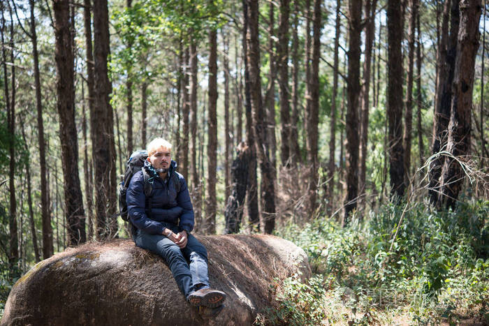 山上的人坐在岩石上看着大自然的美好。男士生活理念