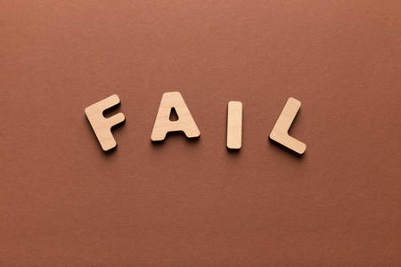 错了字木制字母拼写失败字在棕色背景上照片