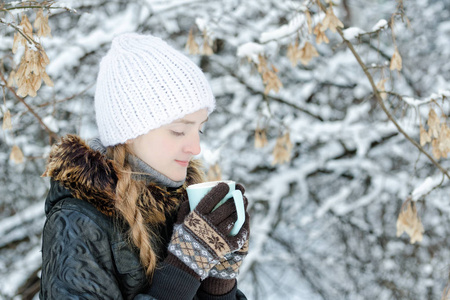女孩在冬天的白帽子与杯茶, 侧面视图