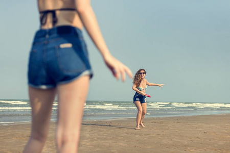 在海滩上玩飞盘的女孩
