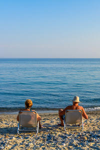 和平夏季海滩夫妇坐着放松享受着质朴的海岸线上的阳光