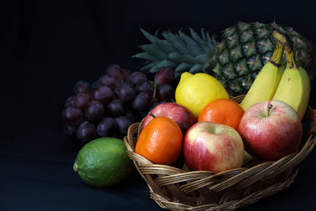 深色食品明暗对比混合水果在柳条篮与暗背景与复制空间左