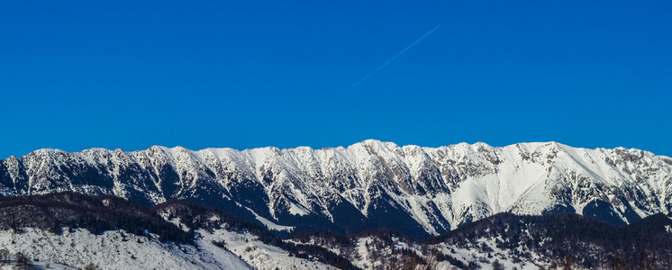 阳光照射左支山山脊与陡坡在日出，罗马尼亚喀尔巴阡山脉被雪覆盖着的关闭视图