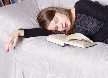 可爱的女孩，同时拿着本书，躺着睡觉