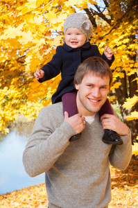 年轻快乐的父亲带着女儿在片秋色的公园