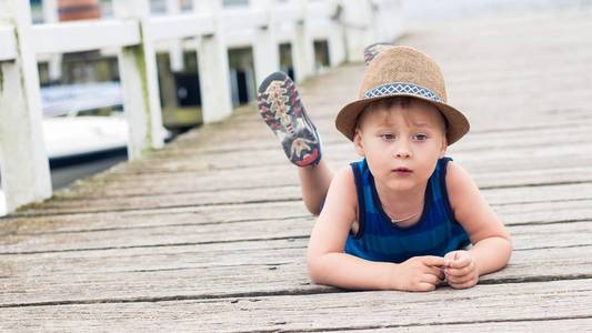 一个可爱的小男孩躺在码头上。海滩上快乐的小男孩。夏天.娱乐.旅游.海