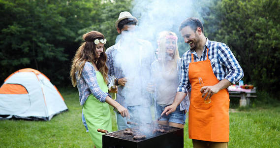 快乐的朋友烧烤肉和享受烧烤聚会户外