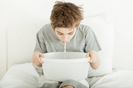 小男孩坐在床上呕吐进碗里照片