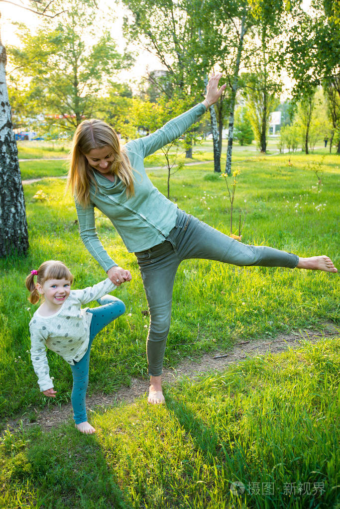 快乐的年轻妈妈和她的小女儿在公园里玩得很开心.