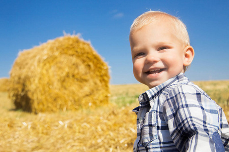 在干草堆的背景下快乐的小男孩。玩得开心, 我