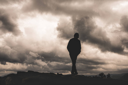 孤独无助男孩剪影在云彩和黑暗的背景.孤独自由绝望或无助感.