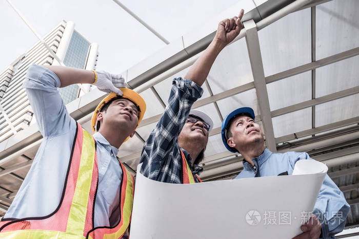 建筑师, 土木工程师和施工现场的工人一起工作在建筑的蓝图上.团队理