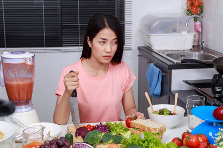 在厨房里用刀子做饭的郁闷女人