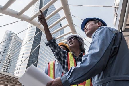 建筑师, 土木工程师和施工现场的工人一起工作在建筑的蓝图上.