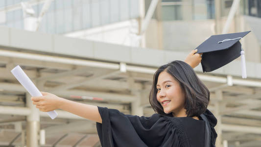 亚洲青年女孩与毕业礼服布料与感觉愉快