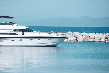 白色豪华游艇, 海上滑行海面.现代昂贵的船附近的岩石防波堤.