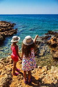 海多岩石的海岸上的两个小姐妹。