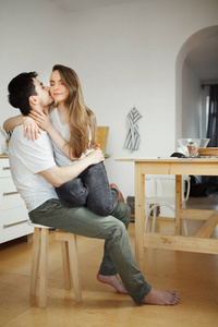 男人亲吻妇女坐在他的腿在厨房