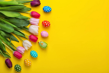 复活节彩蛋与五颜六色的郁金香在黄色背景。复活节假期概念