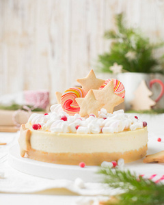 经典的芝士蛋糕 纽约 与圣诞装饰 生姜饼干, 棉花糖和糖果在一个轻木圣诞背景与礼品和灯光。冬季圣诞假期概念