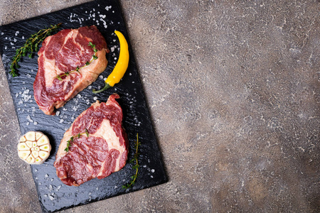 生肉。在迷迭香与香料的砧板上的生牛肉牛排