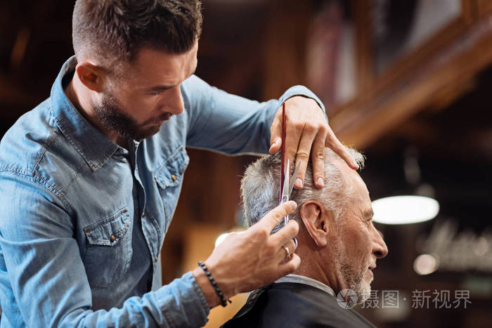 低角度的英俊理发师做他的工作