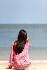 一个年轻的妇女独自思考, 看着大海的背面视图