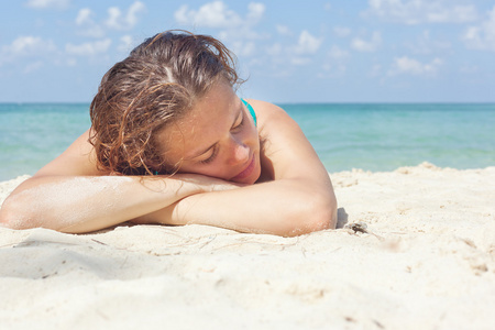 美丽的年轻女子躺在沙岸上的温暖