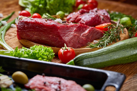 生牛肉在木盘上还有蔬菜, 烹饪托盘过乡村背景, 选择性对焦