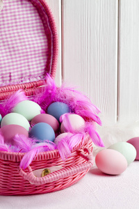 快乐的复活节粉红色篮子充满彩色鸡蛋和羽毛上
