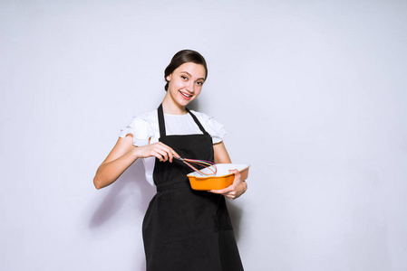 美丽的年轻女子厨师在黑色围裙准备美味的饭菜, 微笑