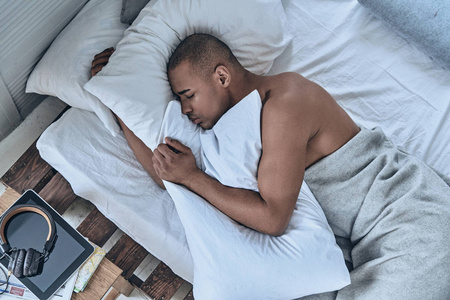 非洲青年男子睡在床上的最高视图