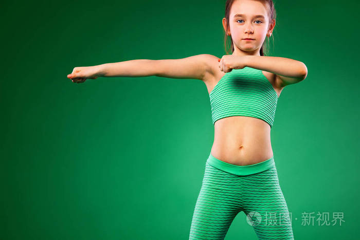 在绿色背景下做健身运动的小女孩