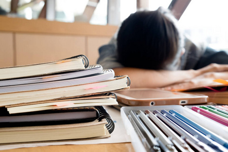特写书籍和疲倦的学生女孩难读和在图书馆睡觉