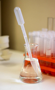 一瓶液体, 玻璃瓶与液体, 玻璃瓶与液体站在桌子上, 桌子在实验室里, 烧瓶与壶嘴, 烧瓶与吸管
