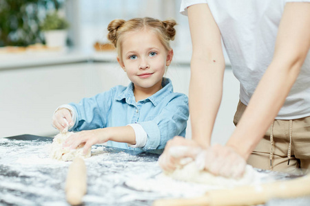 可爱的小女孩帮助她的母亲制作和揉自制的包子自做面团