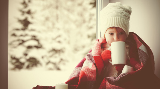 儿童杯热茶在窗口，看着小女孩