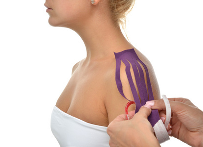 女性肩膀医生用特殊的理疗胶带贴在女性肩膀上照片