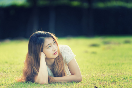 亚洲美丽的年轻女子躺在绿色的草地上