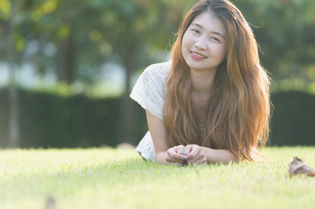 亚洲美丽的年轻女子躺在绿色的草地上