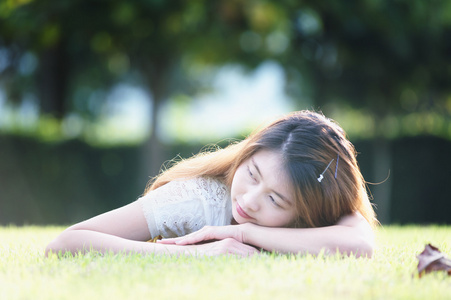亚洲美丽的年轻女子躺在绿色的草地上