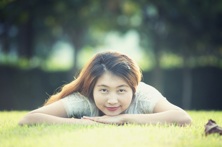 亚洲美丽的年轻女子躺在绿色的草地上