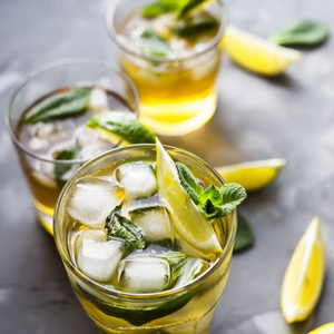 一些玻璃杯与冰, 薄荷和柠檬在灰色的具体背景的冷茶。夏日清凉饮品
