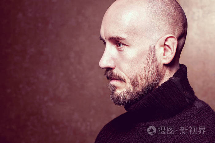 时尚肖像男子站在一个金色的背景下 黑色毛衣 关门了经典风格 光头剃光头 复制空间 工作室拍摄照片 正版商用图片0ga2hq 摄图新视界