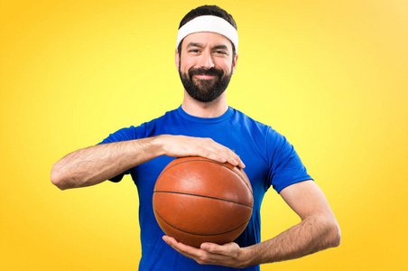 快乐滑稽的运动员与球篮球在五颜六色的 backgr