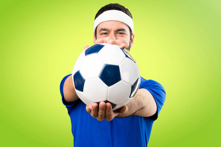 滑稽的运动员拿着一个足球在多彩的背景